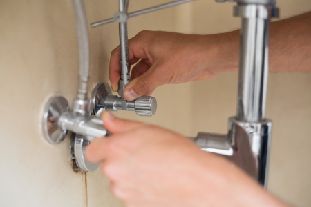 Extreme Close up of a plumbers hands and washbasin drain at bathroomの写真素材