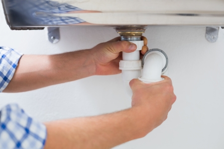 Extreme Close up of a plumbers hands and washbasin drain at bathroomの写真素材