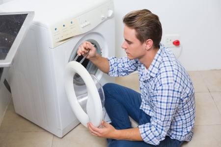 High angle view of a technician repairing a washing machineの写真素材