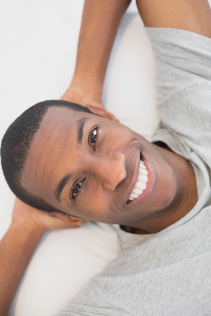 Close up portrait of a smiling young Afro man resting in bed at homeの写真素材