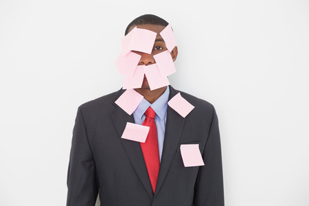 Portrait of an Afro businessman covered in blank notes over white backgroundの写真素材