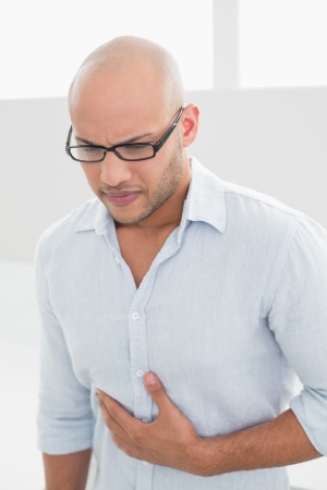 Casual young man suffering from chest pain standing at homeの写真素材
