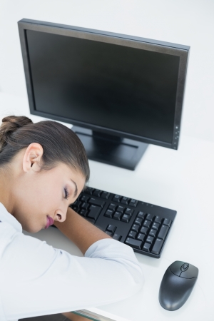 Young businesswoman resting head on keyboard in the officeの写真素材