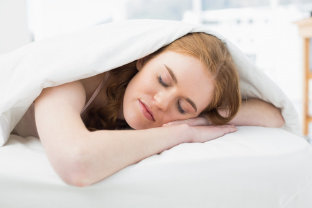 Close up of a pretty young woman sleeping in bed at homeの写真素材