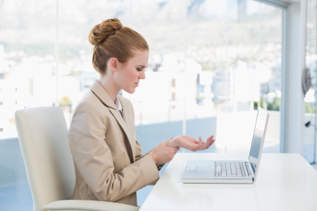 Side view of a young businesswoman suffering from wrist pain in the officeの写真素材