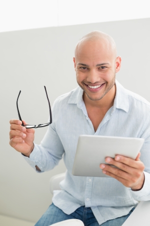 Portrait of a casual smiling young man using digital tablet at homeの写真素材