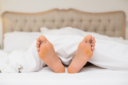 Close up of bare feet in bed at home