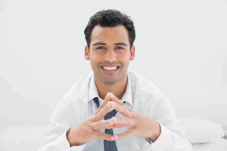 Portrait of a smiling young businessman sitting on bed at homeの写真素材