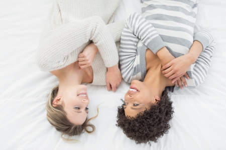 High angle view  of two casual young female friends lying in bed at homeの写真素材