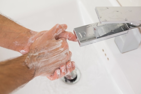 Close up of washing hands with soap under running water at bathroom sinkの写真素材