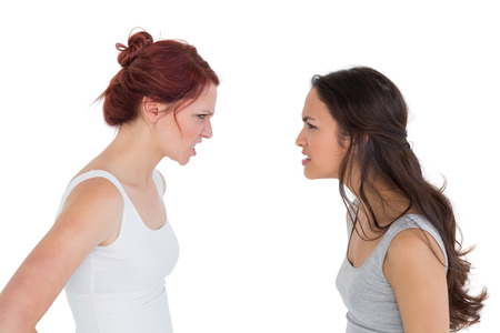 Side view of angry young female friends having an argument over white backgroundの写真素材