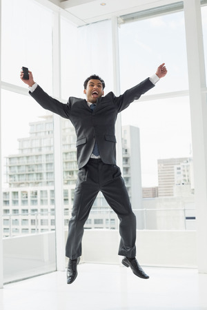 Full length of a cheerful elegant young businessman cheering in a bright officeの写真素材