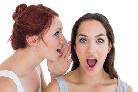 Close-up of two young female friends gossiping over white background