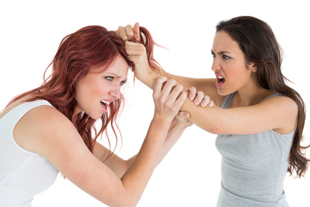 Side view of an angry young woman pulling females hair in a fight over white backgroundの写真素材