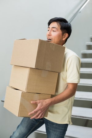 Side view of a young man carrying boxes against staircaseの写真素材