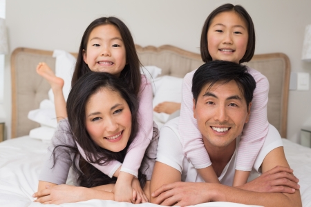 Portrait of a loving family of four lying in bed at homeの写真素材