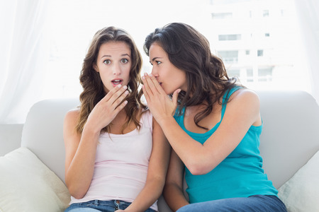 Portrait of relaxed young female friends gossiping in the living room at home