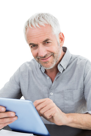 Portrait of a smiling mature businessman using digital tablet against white backgroundの写真素材