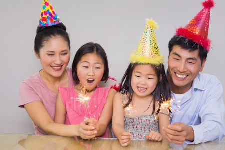 Cheerful family of four playing with firecrackers at a birthday partyの写真素材