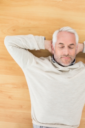 Overhead view of a mature man sleeping on parquet floor at homeの写真素材