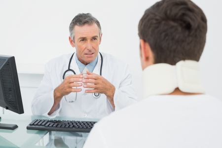 Male doctor in conversation with patient at desk in medical officeの写真素材