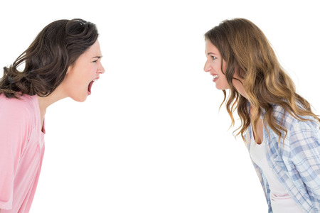 Side view of angry young female friends having an argument over white backgroundの写真素材