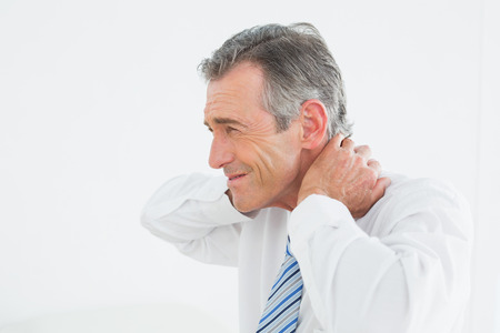 Side view of a mature man suffering from neck pain over white backgroundの写真素材