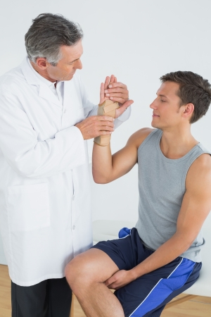 Male doctor examining a patients hand in the medical officeの写真素材