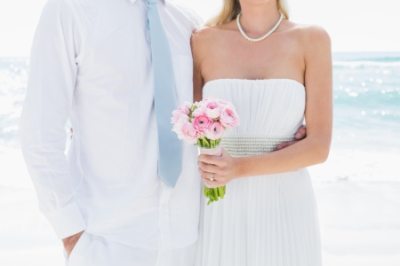 Couple standing together on their wedding day at the beachの写真素材