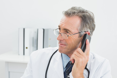 Close-up of a male doctor using telephone at the medical officeの写真素材