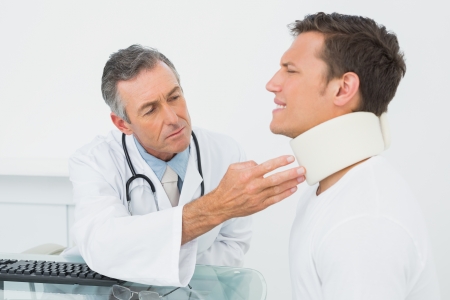 Male doctor examining a patient at desk in medical officeの写真素材