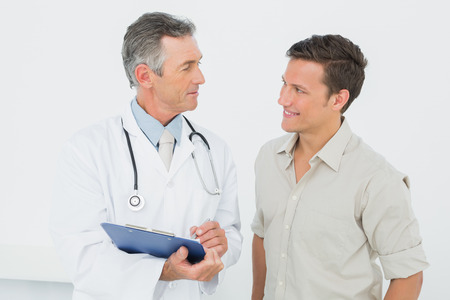 Male doctor discussing reports with patient in medical officeの写真素材