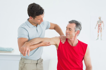 Male physiotherapist massaging mature mans arm in the hospitalの写真素材