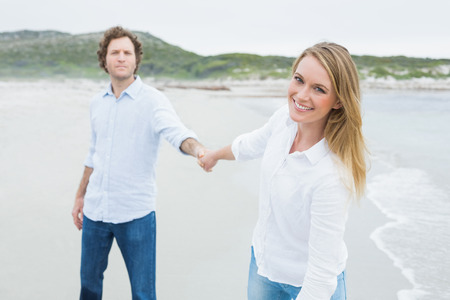 Portrait of a smiling casual young couple holding hands at the beachの写真素材