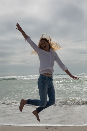 Full length of a casual young woman jumping at the beachの写真素材