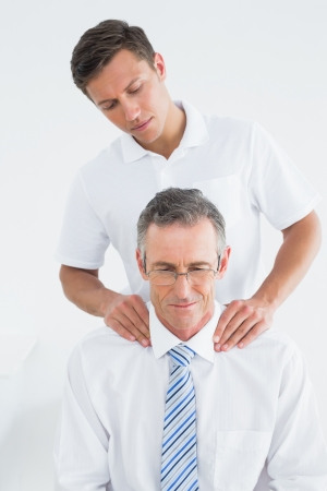 Male chiropractor massaging patients neck over white backgroundの写真素材