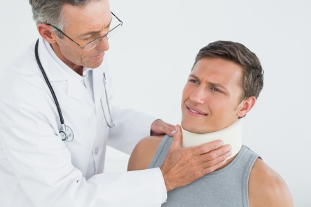 Male doctor examining a patients neck over white backgroundの写真素材