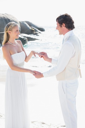 Man placing ring on pretty brides finger at the beachの写真素材