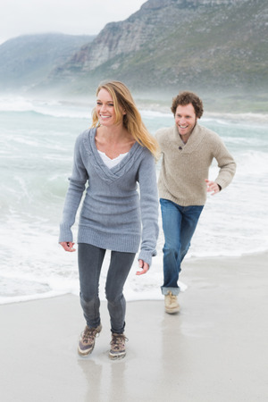 Full length of a happy casual young couple running at the beachの写真素材