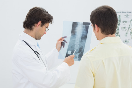 Male doctor explaining spine x-ray to patient in the medical officeの写真素材