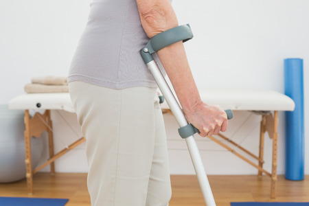 Close-up mid section of a woman with crutches standing in the hospitalの写真素材