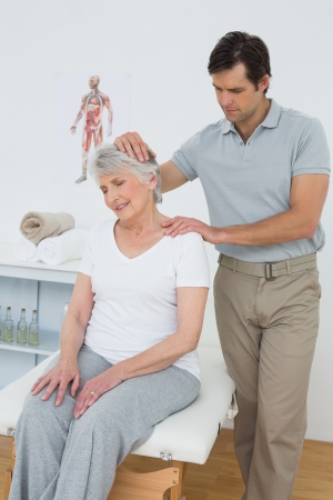 Senior woman getting the neck adjustment done in the medical officeの写真素材