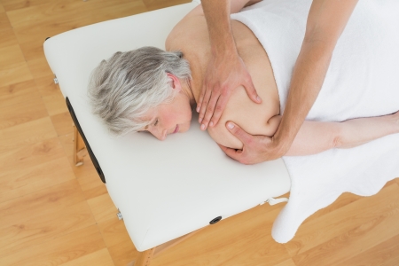 High angle view of a physiotherapist massaging a senior woman's back in the medical officeの写真素材