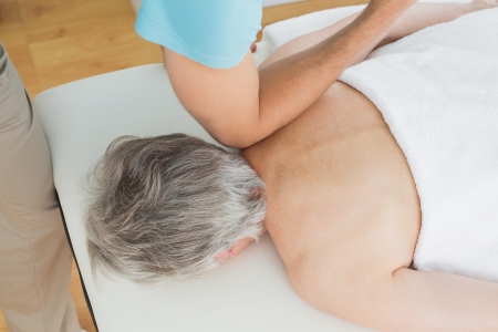 High angle view of a physiotherapist massaging a senior woman's back in the medical officeの写真素材