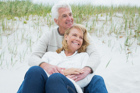Romantic senior man and woman relaxing on sand at the beach