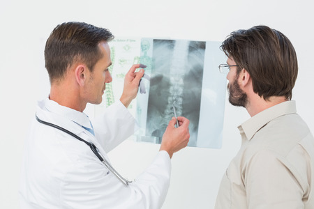 Male doctor explaining spine x-ray to patient in the medical officeの写真素材