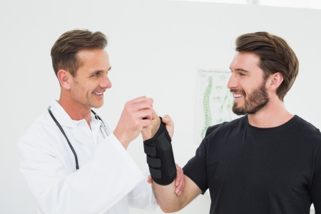 Male physiotherapist examining a young man's wrist in the medical officeの写真素材