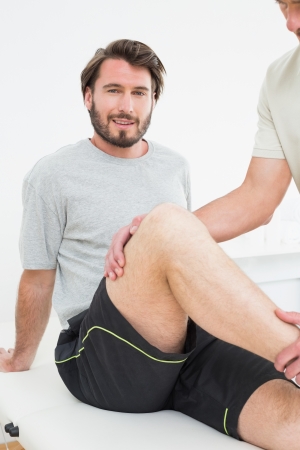 Portrait of a young man getting his knee examined at the medical officeの写真素材