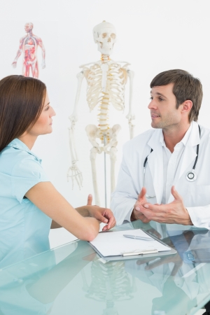 Male doctor listening to patient with concentration at desk in medical officeの写真素材