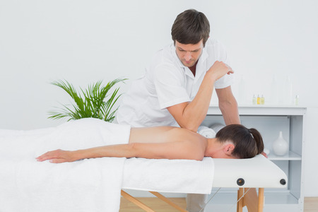 Male physiotherapist massaging woman's back in the medical officeの写真素材